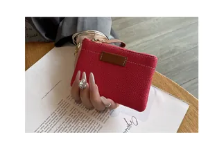Gros plan d'un porte-monnaie en cuir magenta avec détails dorés et dragonne pratique