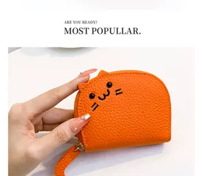 Detailed view of cute cat embroidery on small orange textured leather coin purse.