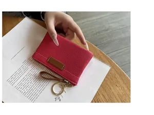 Vue détaillée d'un porte-monnaie fin en cuir rose avec fixation porte-clés dorée