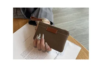 Vue détaillée d'un petit porte-monnaie en cuir marron avec une dragonne élégante et fine