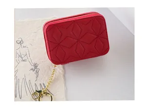 Detailed macro view of a small red quilted makeup bag with a gold chain and keyring.