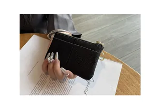 Gros plan sur le porte-monnaie slim en cuir grainé noir avec un anneau doré détaillé
