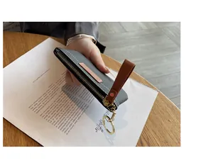 Vue détaillée du profil latéral ultra-fin et de la texture cuir du petit porte-monnaie gris.