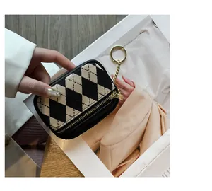 Detailaufnahme einer Mini-Geldbörse mit Rautenmuster, Goldreißverschluss und Ring.