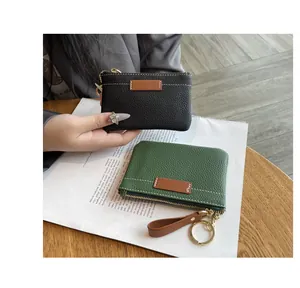 Vue détaillée de mini porte-monnaie en cuir noir et vert avec anneaux porte-clés dorés