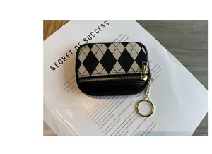 Detail der Mini-Münztasche mit Rautenmuster, goldenem Reißverschluss und Schlüsselanhänger