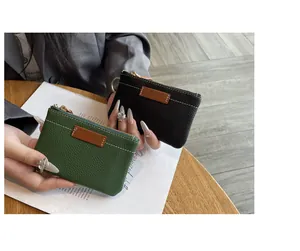 Gros plan de petits porte-monnaie en cuir grainé vert et noir avec fermetures dorées.