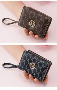 Detail of women's trifold short wallet in brown and black with M monogram pattern