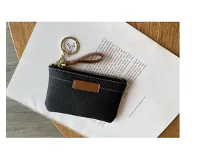 Vue détaillée d'un porte-monnaie en cuir noir avec porte-clés doré sur un magazine.