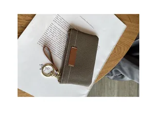 Gros plan d'un porte-monnaie ultra-plat en cuir gris avec porte-clés doré