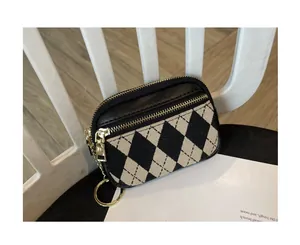Nahaufnahme einer stylischen schwarz-weißen Mini-Geldbörse mit Rautenmuster und Gold-Zipper