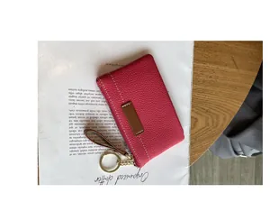 Un gros plan détaillé d'un porte-monnaie en cuir rose avec un anneau de clé doré