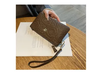 Pochette élégante en cuir marron avec fleurs embossées sur un magazine lifestyle.