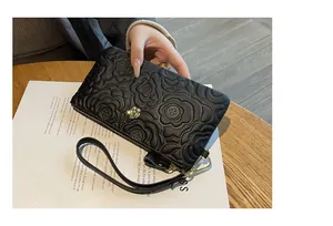 Vue détaillée d'une pochette en cuir véritable noir avec motif de fleur de camélia embossé