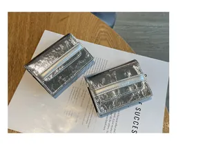 Detailed view of two silver metallic leather card holders on a magazine background