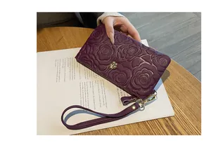 Vue détaillée d'une pochette en cuir violet avec un motif camélia élégant et raffiné.