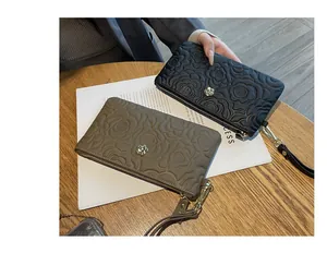Vue détaillée de pochettes en cuir à motif floral embossé en noir et taupe sur bois