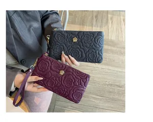 Détail de portefeuilles longs en cuir gaufré noir et bordeaux avec motifs floraux