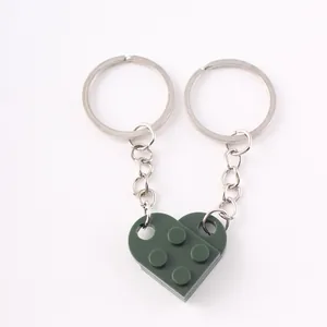 Close-up of a dark green heart-shaped building block keychain on a white background