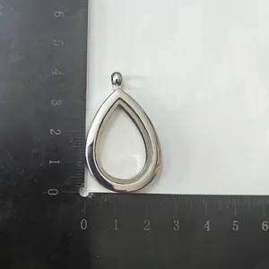 Silver water drop floating locket pendant shown with measurements on a scale ruler