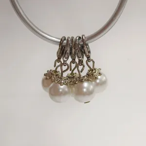 Detailed view of white pearl charms with silver lobster clasps and flower caps for DIY crafts