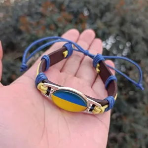 Detail view of the Ukrainian flag glass cabochon on a hand-woven leather bracelet