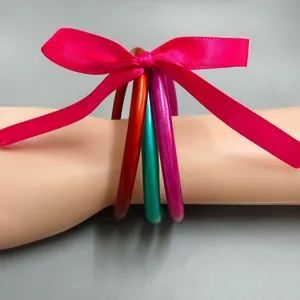 Detailaufnahme farbenfroher Silikon-Jelly-Armbänder mit einer leuchtend rosa Schleife