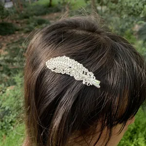 Elegant silver feather hair clip with sparkly rhinestones shown on hair for styling