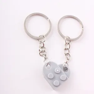 Detailed view of gray interlocking heart-shaped building block keychains on white background