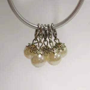Detailed view of pearl pendants featuring ornate silver flower caps and lobster clasps.
