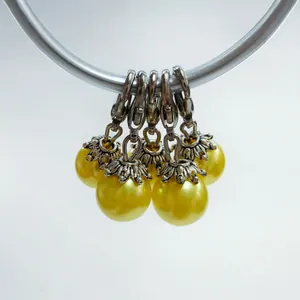 Close-up of five yellow pearl pendants with silver lobster clasps and flower caps
