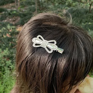 Detailed view of a sparkling rhinestone butterfly hair clip worn on long dark hair