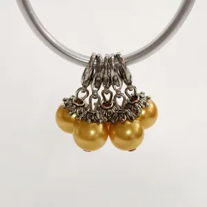 Close-up of five golden pearl charms featuring lobster clasps and ornate silver caps