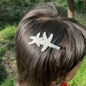 Close-up of double rhinestone starfish hair clip worn on dark hair in a natural outdoor setting.