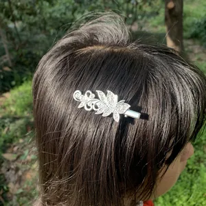 Macro detail of an elegant silver butterfly hair clip with rhinestones worn on dark hair.