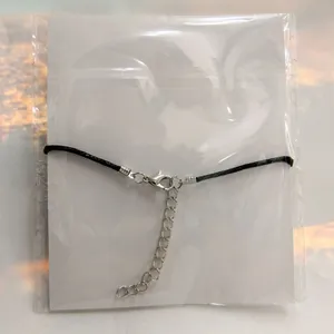 Detalle del cierre de la pulsera de cordón negro y cadena de extensión.