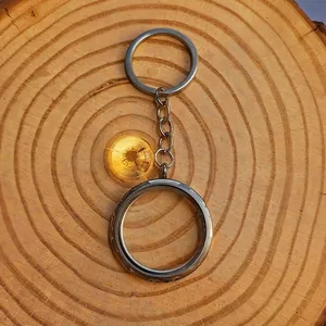 Gedetailleerd zicht van een zilveren floating locket sleutelhanger op hout