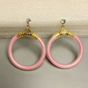 Macro-weergave van fonkelende roze glitter jelly oorringen met goudkleurige getextureerde accenten