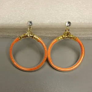 Detailopname van modieuze oranje glitter jelly creolen met gouden accenten en strass