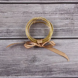 Elegant gold glitter filled silicone bangle bracelet set with a decorative tan ribbon bow