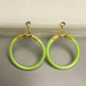 Detailopname van neon groene glitter gevulde oorringen met goudkleurige metalen accenten