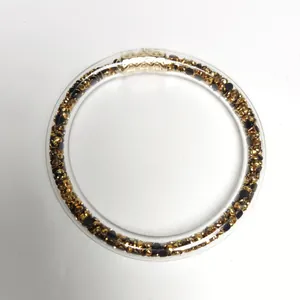 Detalle de brazalete de PVC de 9 mm relleno de elegantes piedras doradas y negras