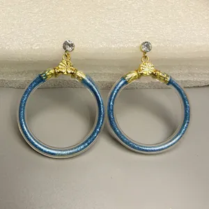 Detailweergave van blauwe glitter jelly oorringen met een gouden levensboom design