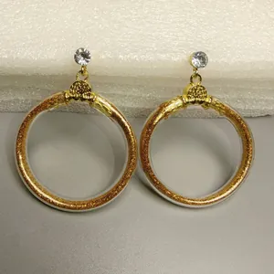 Detailweergave van gouden glitter jelly oorbellen met kristallen accenten.