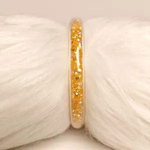 Primer plano de un brazalete jelly de PVC amarillo con circonitas en piel