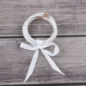 Multilayer white glitter silicone bracelets with a decorative white satin ribbon bow.