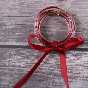 Elegant multilayer red glitter silicone bangles with a decorative red satin ribbon bow set.