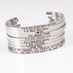 Close-up of engraved inspirational quotes on stainless steel C-shaped cuff bracelets
