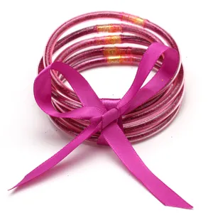 Set of five pink glittery silicone bangles tied with a matching magenta silk ribbon bow.