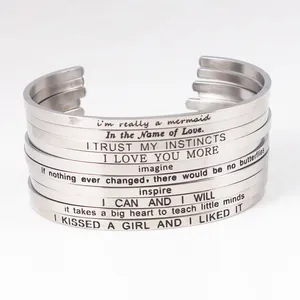 Detail view of stacked stainless steel cuff bracelets with inspirational engravings.